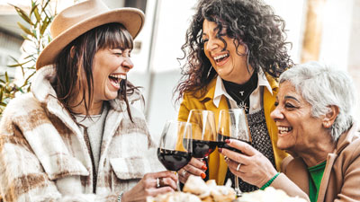 Active adult women laughing and toasting with wine glasses.