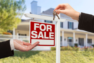 Upscale suburban house with for sale sign, human hands exchanging keys.
